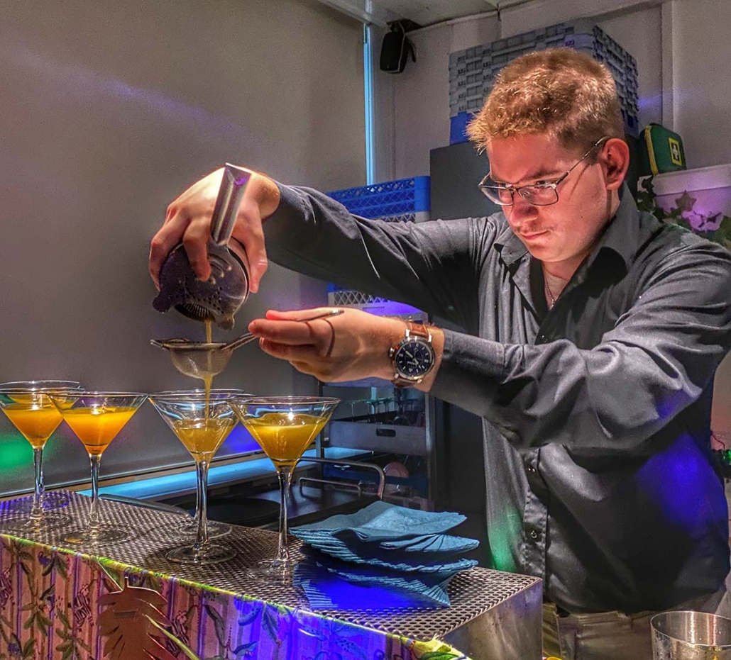 Nuori mies siivilöi juomaa cocktail-lasiin opetusbaarissa Perho Liiketalousopistossa.