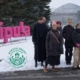 A group of people standing outdoors in front of big pink logo.