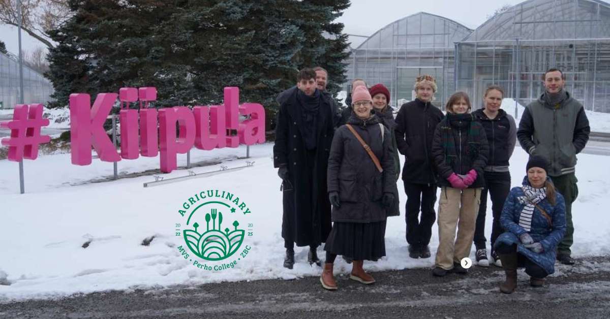 A group of people standing outdoors in front of big pink logo.